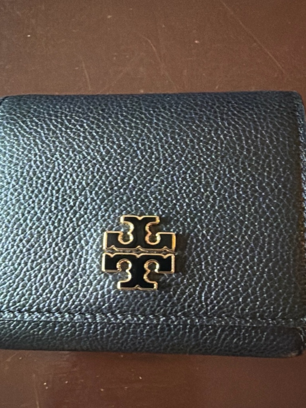 Tory Burch Britten Compact Wallet in black pebbled leather.